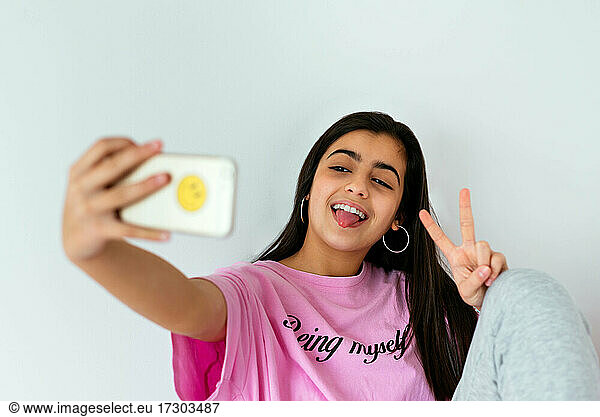 Teenage girl using smartphone on bed and taking photos