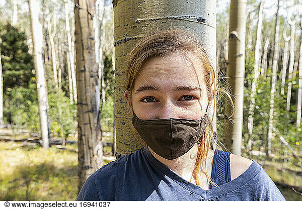 Teenage girl wearing COVID-19 mask in forest of Aspen trees