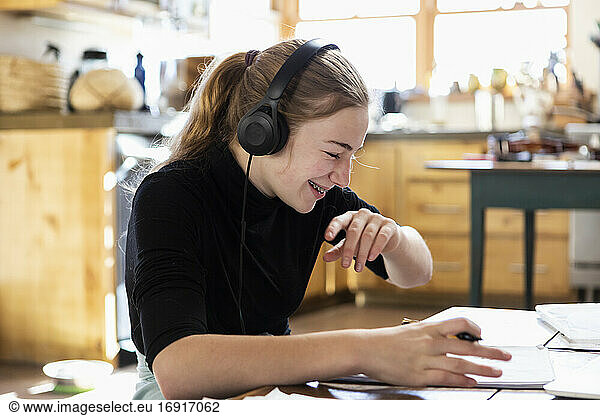 Teenage girl wearing headphones  drawing on paper