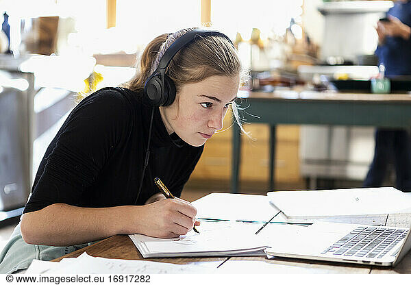 teenage girl wearing headphones  drawing on paper