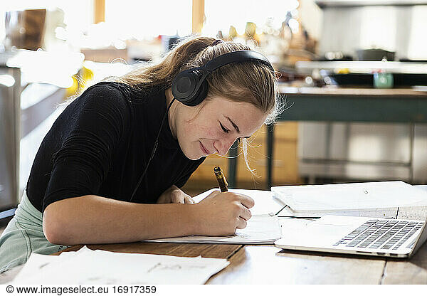 Teenage girl wearing headphones drawing on paper