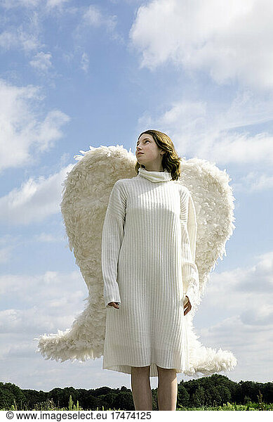 Teenage girl wearing white wings contemplating on sunny day