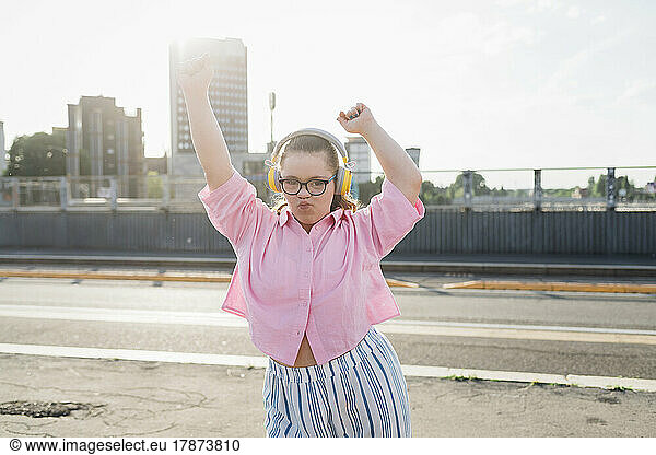 Teenage girl with headphones listening music and dancing on street