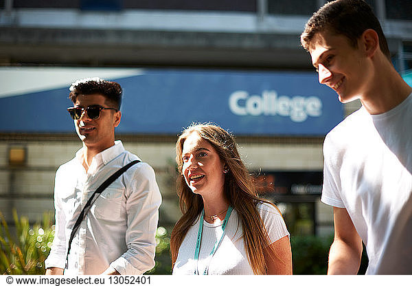 Teenage girl with young male higher education students leaving college campus