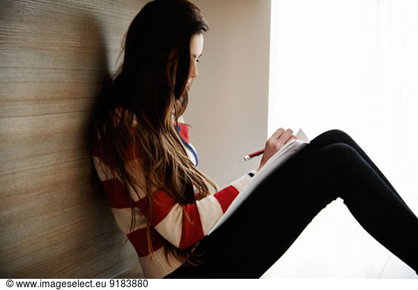 Teenage girl writing in notebook