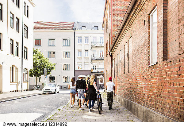 Teenage girls and teenage boys (14-15) walking in city