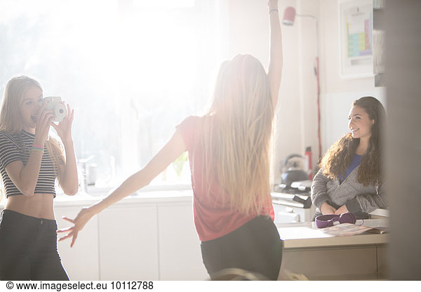 Teenage girls dancing and photographing in kitchen