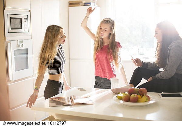 Teenage girls dancing in sunny kitchen