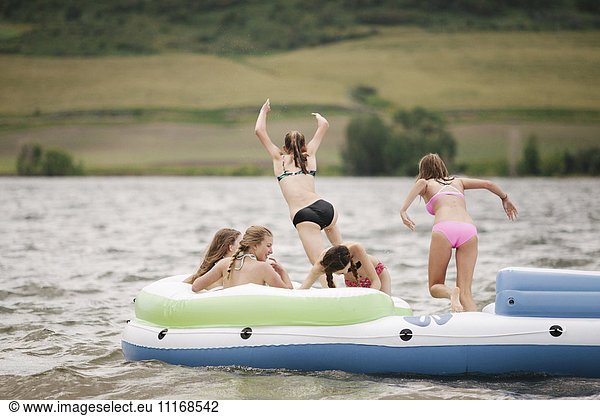 Teenage girls in an inflatable dinghy on a lake.