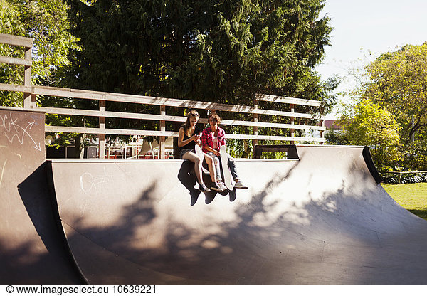 Teenage girls sitting on ramp at park