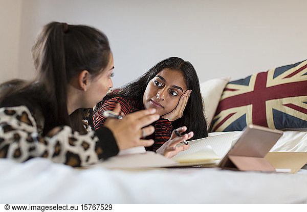 Teenage girls studying  talking on bed