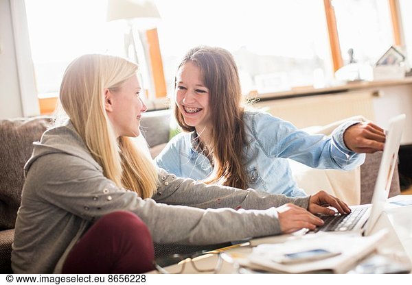Teenage girls using laptop at home