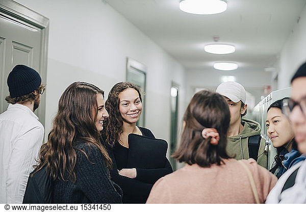 Teenage high school students talking while standing in corridor