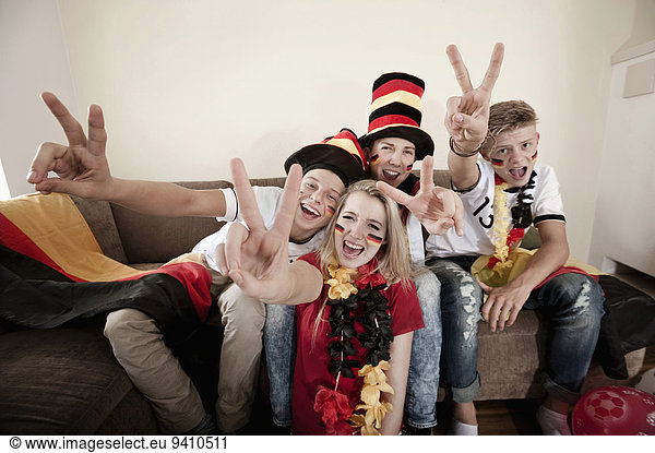 Teenage soccer fans posing in living room