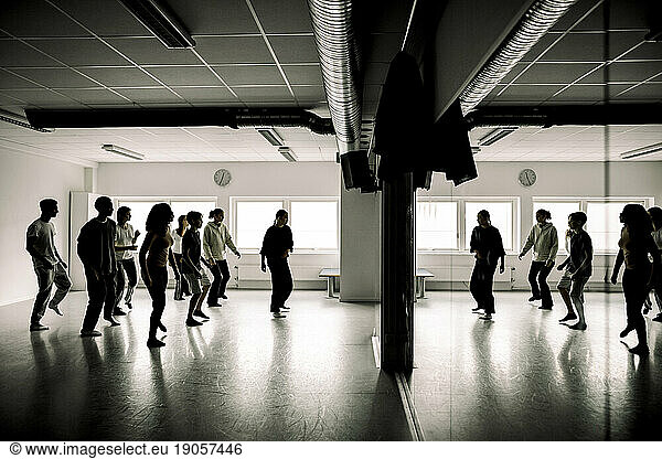 Teenage students rehearsing with female teacher in dance studio at high school