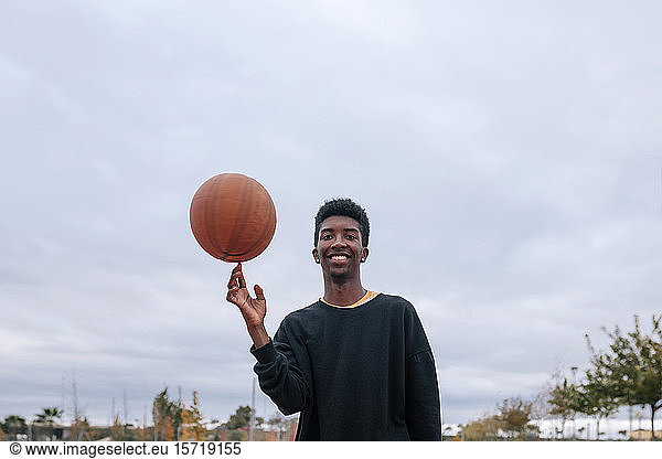 Teenager balanciert Basketball auf seinem Finger