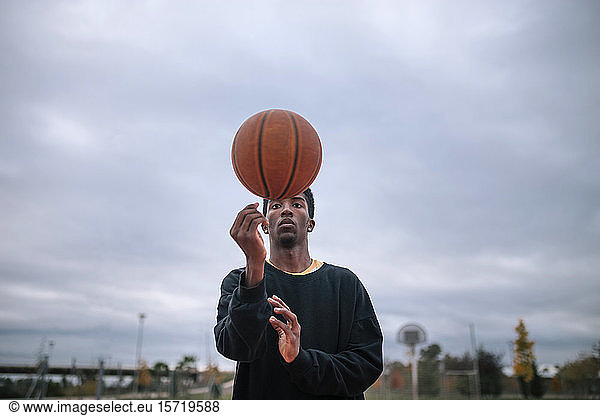 Teenager balanciert Basketball auf seinem Finger