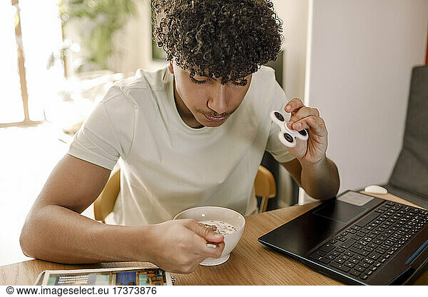 Teenager boy having food while sitting at table in living room