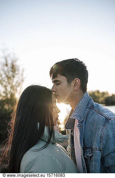 Teenager  der seine Freundin im Gegenlicht küsst