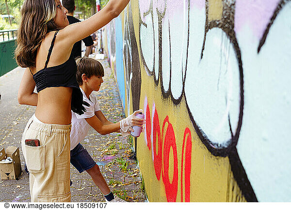 Teenager drawing graffiti on the wall. Street art.