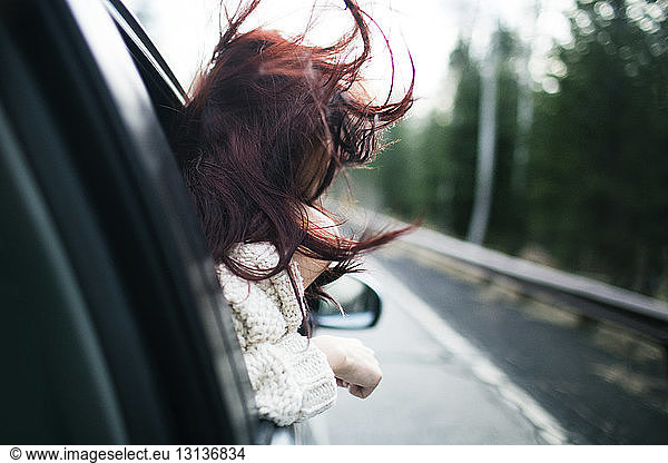 Teenager enjoying wind while peeking through car window