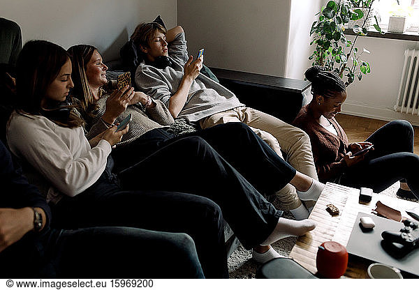 Teenager-Freunde nutzen soziale Medien auf Smartphones  während sie zu Hause sitzen