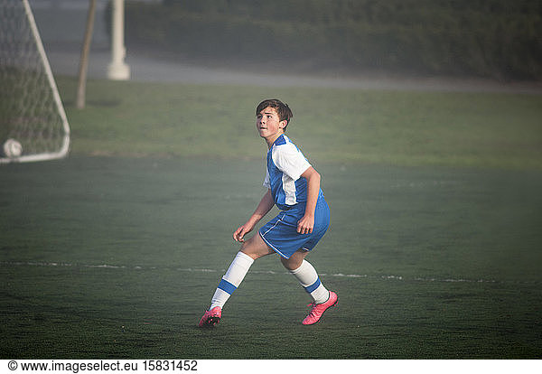 Teenager-Fussballer bereit zur Verteidigung auf nebligem Feld