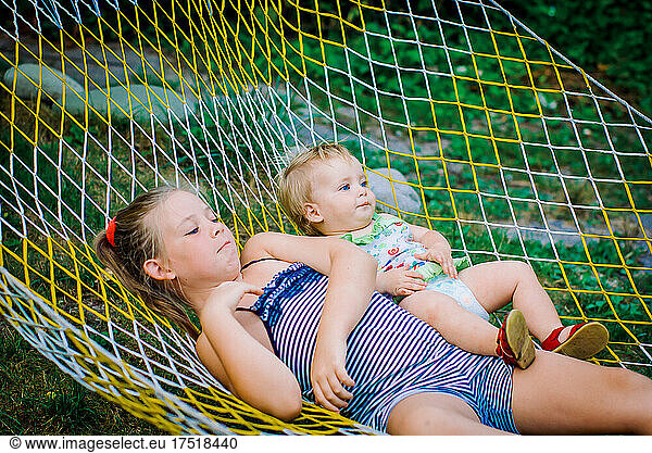 Teenager girls and child having fun in the garden on a hammock