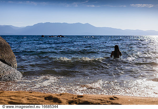 Teenager im Bergsee schwimmt im Sonnenschein - Reisen und Abenteuer