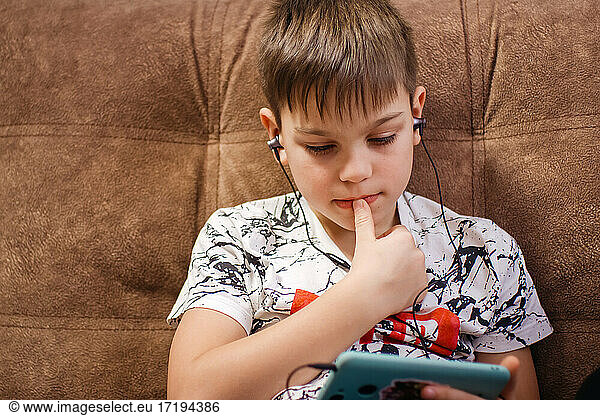 Teenager in headphones looks at phone screen