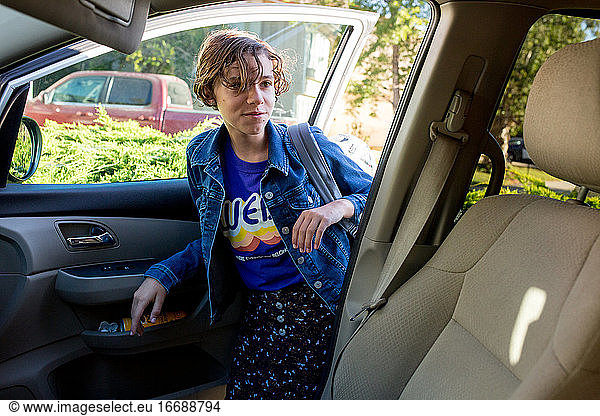 Teenager-Mädchen mit kurzen Haaren steigt mit ihrem Rucksack ins Auto