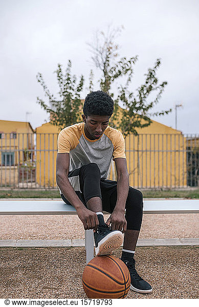 Teenager mit Basketball  Schuhe binden