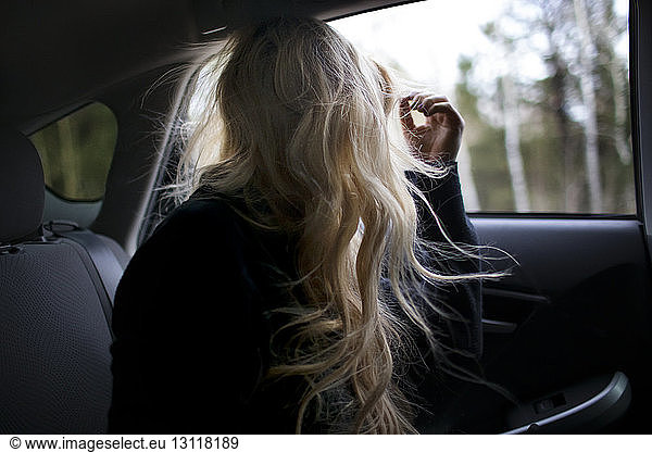 Teenager mit langen Haaren schaut durch das Autofenster