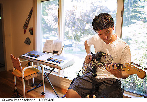 Teenager practicing electric guitar at home