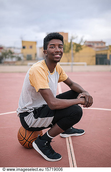 Teenager sitzt auf Basketball