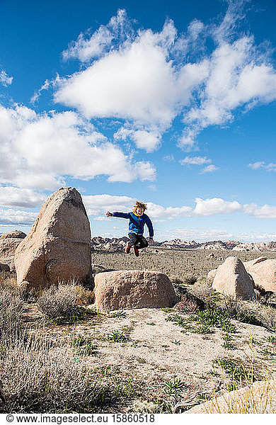 Teenager springt von großem Stein im Joshua-Tree-Nationalpark