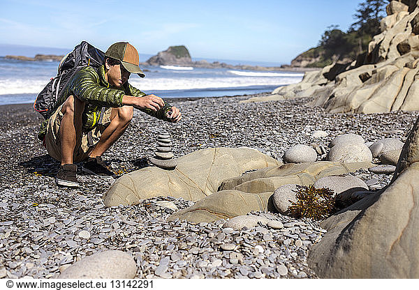 Teenager stapelt Steine am Meeresufer am Strand