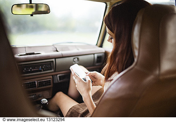 Teenager using phone while sitting in car