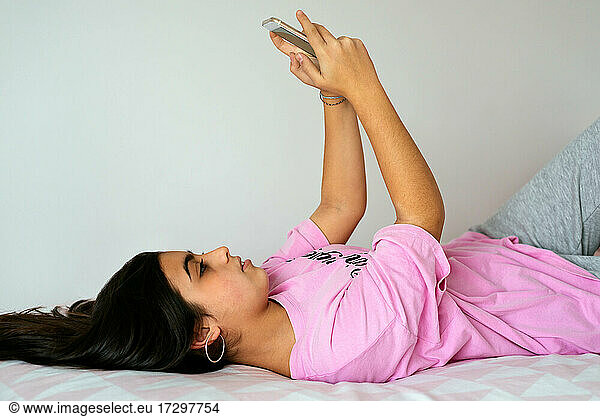 Teenager using smartphone on bed