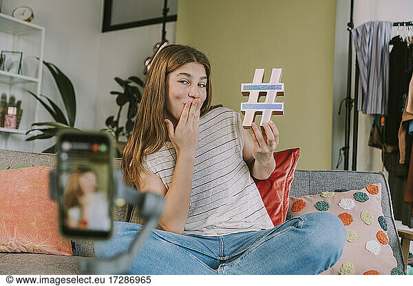Teenagerin hält Hashtag-Symbol beim Filmen zu Hause