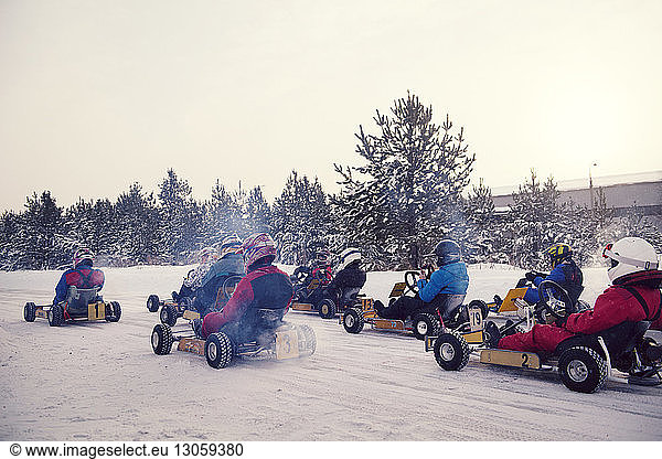 Teenagers enjoying go-carts racing on snow covered field