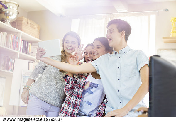 Teenagers taking selfie with digital tablet in room