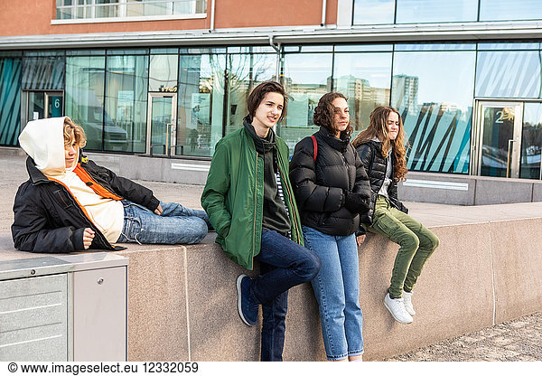Teenagers wearing warm clothing against building in city
