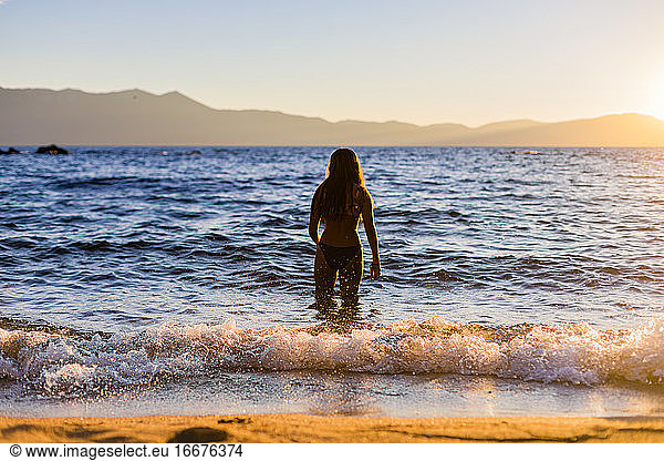 Teenagerschwimmen im Bergsee bei Sonnenuntergang oder Sonnenaufgang für Reisen und Abenteuer