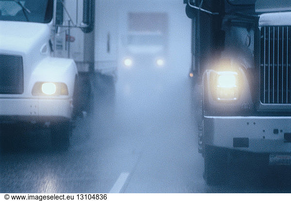 Teilansicht eines großen Lastkraftwagens  der unter gefährlichen Schnee- und Regenbedingungen auf einer Autobahn fährt.