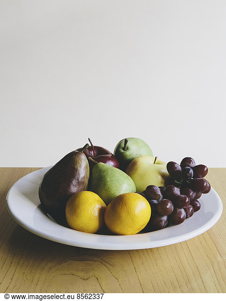 Teller mit frischem Obst aus biologischem Anbau (Mandarinen  Trauben  rote Bartlettbirne  grüne Anjou-Birnen  Äpfel)