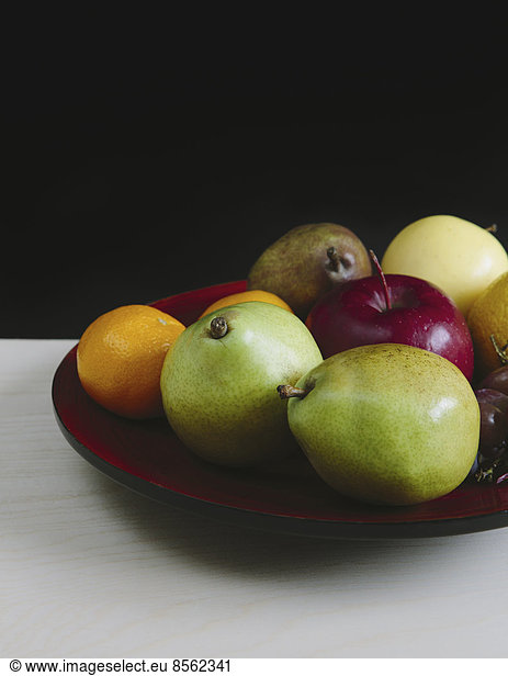 Teller mit frischem Obst aus biologischem Anbau (Mandarinen  Trauben  rote Bartlettbirne  grüne Anjou-Birnen  Äpfel)