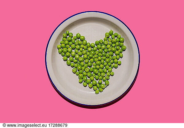 Teller mit grünen Erbsen in Form eines Herzens
