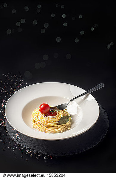 Teller mit Spaghetti und Kirschtomaten mit beleuchtetem Backgr