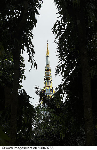 Temple spire against clear sky seen through trees